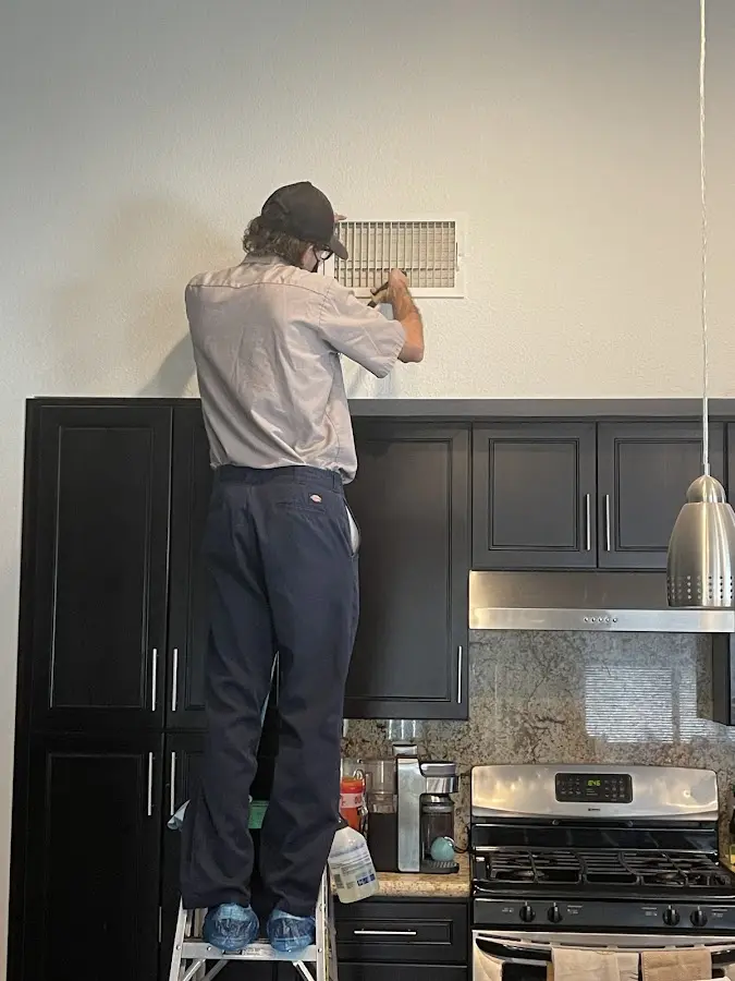 Technician inspecting an air vent during HVAC service in Pico Rivera